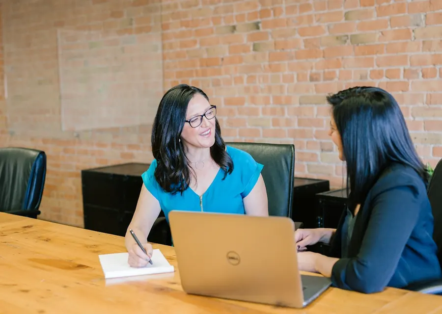 Two people in a business meeting at a table with a laptop