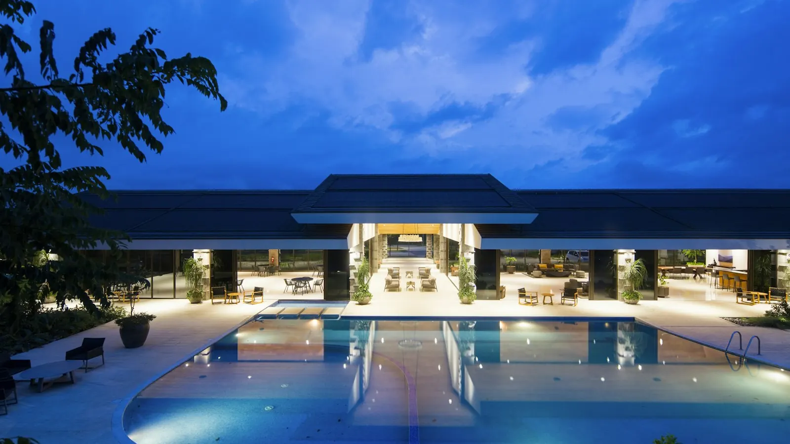 Resort pool and lobby building lit at dusk